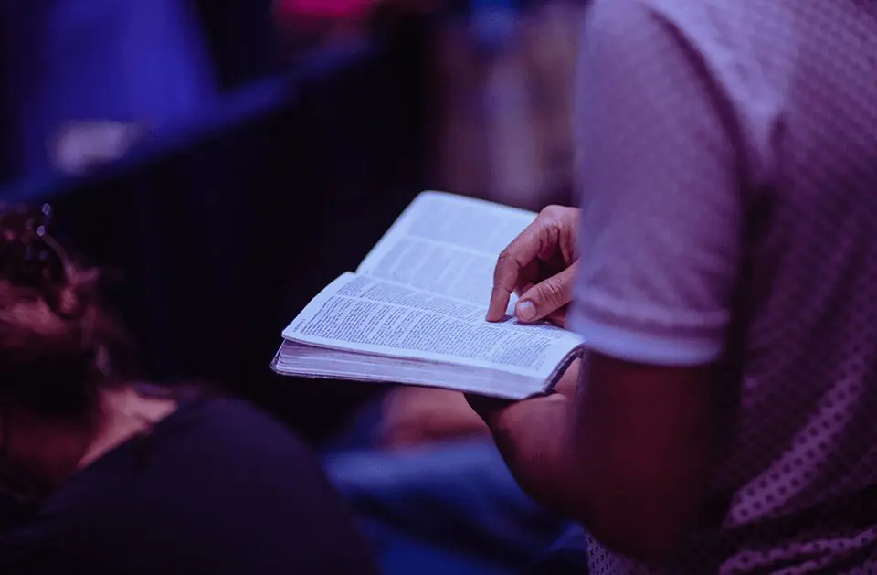 A person holding a bible in front of a crowd.