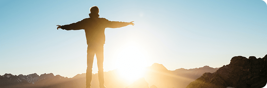 A man standing on top of a mountain with his arms outstretched.