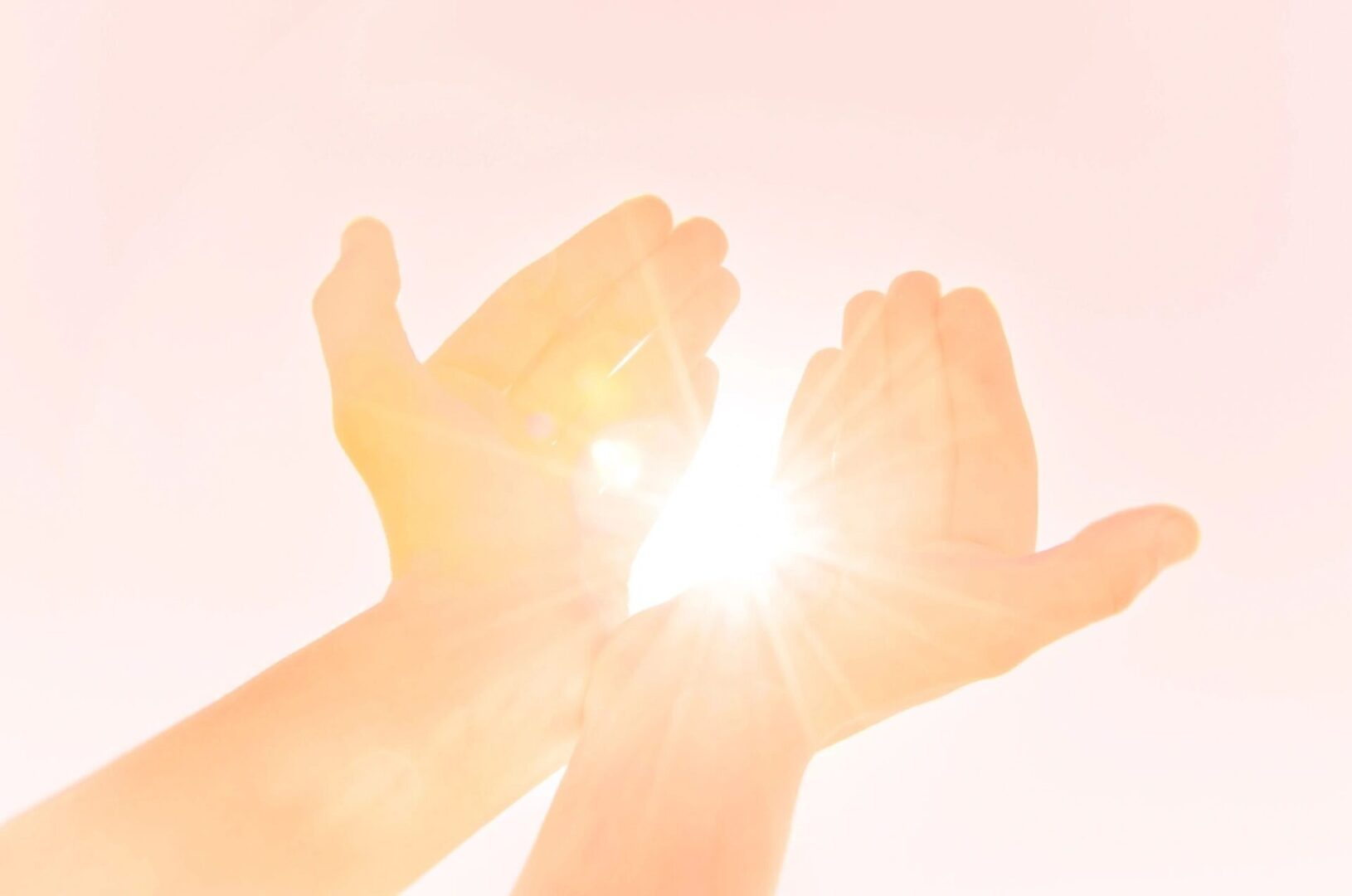 A pair of hands reaching up to the sun.