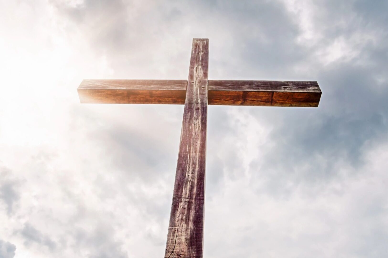 A wooden cross against a cloudy sky.